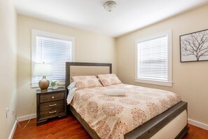 A bedroom with a bed, nightstand, lamp, and a framed picture on the wall. - @ Marbella Lane-Spacious 5BR Home 11-Min to Levi's (San Jose)