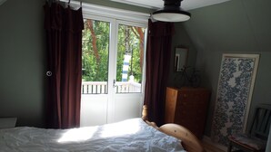 Un dormitorio con una cama grande, un aparador de madera, una silla y una ventana con cortinas.