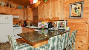 Una cocina con armarios de madera, una isla central con taburetes de bar y un cartel antiguo en la pared.