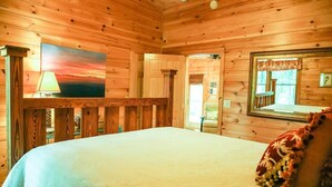Una habitación de cabaña de madera con una cama, un cuadro, una lámpara y un espejo.
