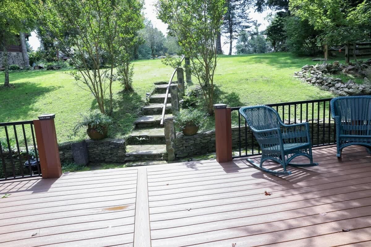 Una terraza de madera con una escalera de piedra que baja a un jardín de césped.