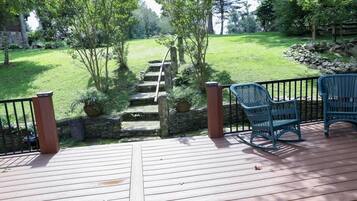 Una terraza de madera con una escalera de piedra que baja a un jardín de césped.