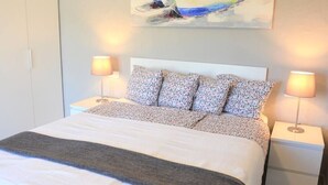 A neatly made bed with a floral bedspread and two bedside lamps. - Casa La Moringa - Holiday house close to the beach (Los Caideros)