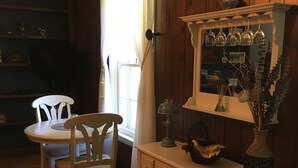 A wooden-paneled room with a dining table and chairs, a cabinet with glassware, and a window with curtains. - Quiet home on horse farm, halfway between Paducah & Wickliffe. Close to 60 & 286 (Kevil)