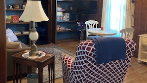 A cozy living room with a sofa, a coffee table, a lamp, a bookshelf, and a television. - Quiet home on horse farm, halfway between Paducah & Wickliffe. Close to 60 & 286 (Kevil)