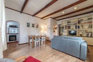 A living room with a sofa, a dining table with chairs, a kitchen area, and a bookshelf with various items. - GuestHost - Apartment located on the second floor of a typical period building without a lift.In 55 square meters of space it comfortably accommodates 3 people.Located in a strategic position a short distance from the Colosseum, the Colle Oppio Park and  (Roma)
