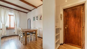 Un comedor con mesa y sillas de madera, una ventana con cortinas y una puerta de madera.