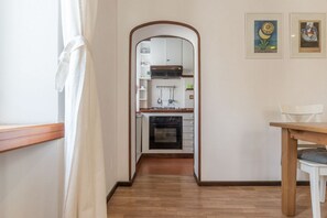 A narrow hallway leading to a kitchen with white cabinets, a black oven, and a wooden table. - GuestHost - Apartment located on the second floor of a typical period building without a lift.In 55 square meters of space it comfortably accommodates 3 people.Located in a strategic position a short distance from the Colosseum, the Colle Oppio Park and  (Roma)