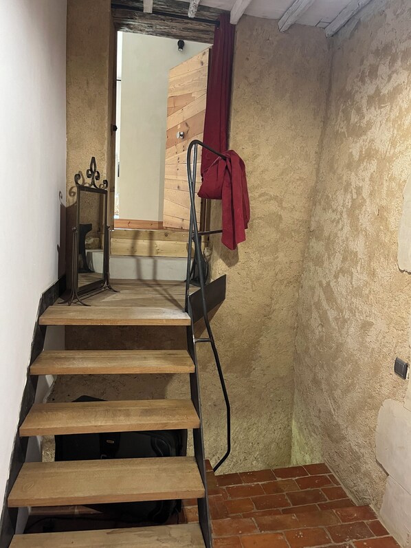 A staircase with wooden steps leading to a room with a wooden wall and a red curtain.
