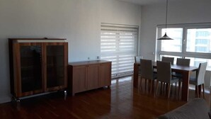 Un'ampia zona giorno con un armadio in legno, un tavolo da pranzo con sedie e un'ampia finestra con tende.