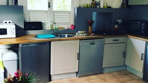 Een kleine keuken met een spoelbak, een magnetron, een vaatwasser en een fornuis.