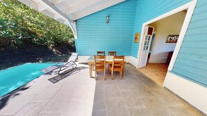 Een terras met zwembad, een tafel met stoelen en een deur naar een binnenruimte.