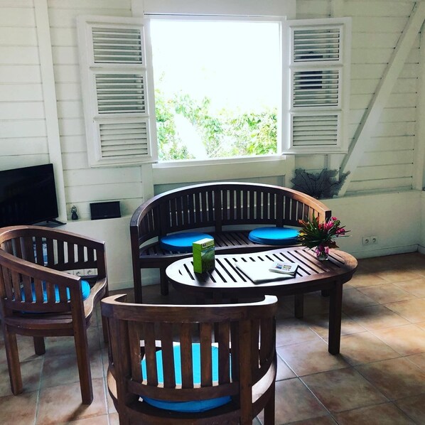 Una habitación con una mesa y sillas de madera, una ventana con contraventanas y vistas a zonas verdes.