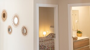 A room with exposed wooden beams, a geometric light fixture, and a bed with a colorful headboard.