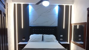 A modern bedroom with a large bed, a ceiling fan, and a marble-patterned wall. - Residence Tropical Garden - Cozy Family Apartment (1)  (Boca Chica)