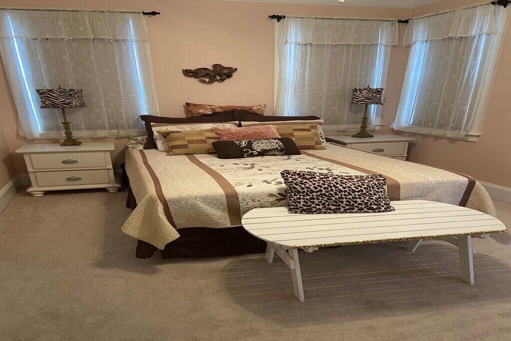 A bedroom with a bed, bedside tables, a bench, and curtains.