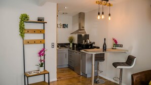 A modern kitchen with a central island, stainless steel appliances, and a hanging light fixture. - BnB Epernay   Studio 86   Your Cozy Nest for Two in Épernay (Épernay)