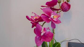 A glass vase with pink orchids on a dark tiled surface.