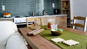 A kitchen with a wooden table, a green tablecloth, and various kitchen items.