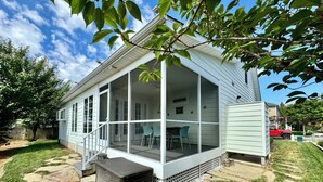 Een huis met een overdekte veranda, een pad van stenen en een omheinde achtertuin.