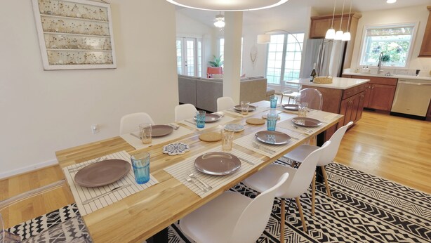 Een moderne eetruimte met een lange houten tafel voor zes personen, omringd door witte stoelen.
