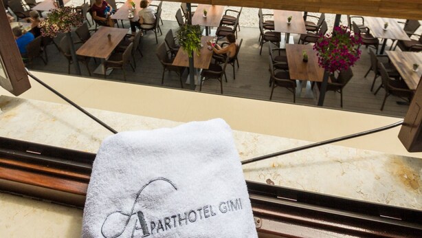 A terrace with tables and chairs overlooking a beach and the sea. - Aparthotel Gimi (Moscenicka Draga)