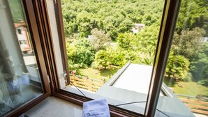 A window view of a lush green landscape with a wooden deck and a towel labeled "Parthotel Gimi" on the windowsill. - Aparthotel Gimi (Moscenicka Draga)