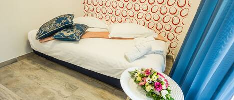 A neatly made bed with pillows and a floral arrangement on a small table beside it.