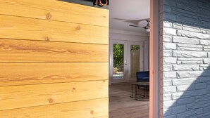 A wooden wall with the number 16, a stone wall, a ceiling fan, and a view of a room with a blue chair and a table. - 4411 Inn & Suites (Michigan City)