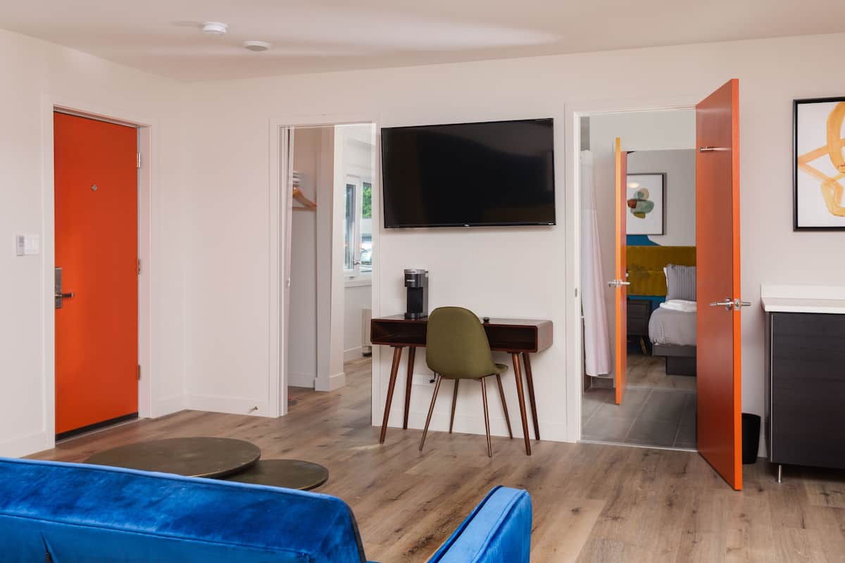 Un salon moderne avec un canapé bleu, une table basse et un téléviseur à écran plat fixé au mur.