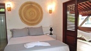 Una cama bien hecha con una toalla, un tapiz tejido y dos lámparas de pared.