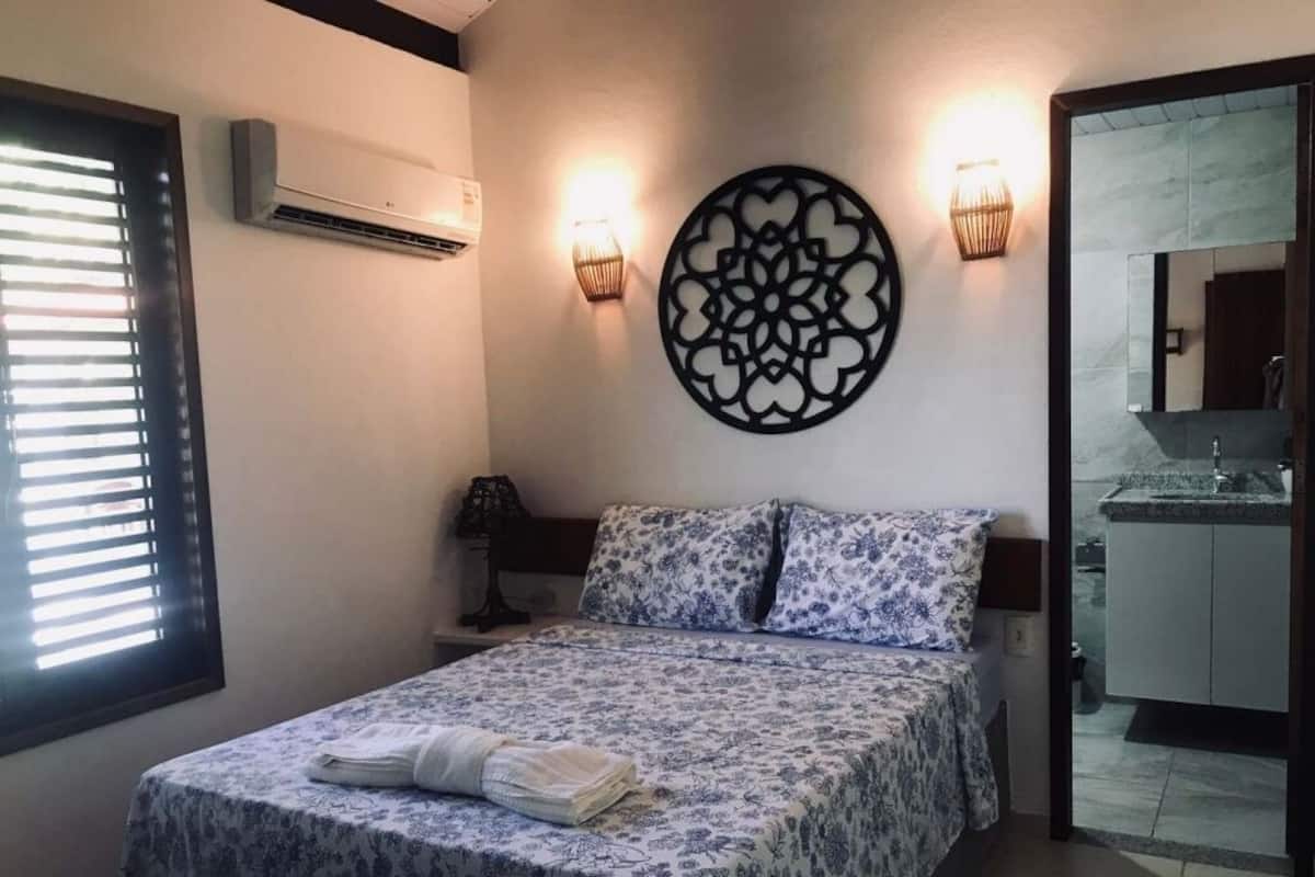 Une chambre à coucher comprenant un lit, un climatiseur fixé au mur, deux appliques murales et un élément décoratif mural.