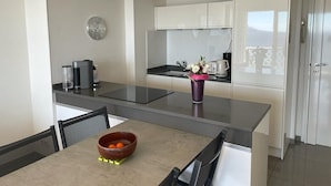 A modern kitchen with a central island, white cabinets, and a dining area with a table and chairs.