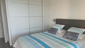 A bedroom with a bed, grey headboard, and striped bedding.