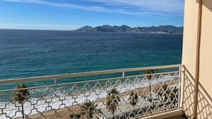 A balcony with a view of the sea and distant mountains.