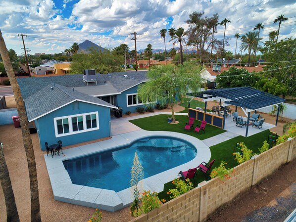 A residential property with a swimming pool, patio furniture, and a covered outdoor seating area.