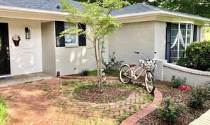Ein Wohnhaus mit Pflasterauffahrt, einem draußen abgestellten Fahrrad und einem kleinen Baum im Vorgarten.