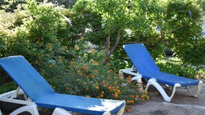 Two blue lounge chairs with white frames, positioned on a concrete surface with a garden in the background. - Beach<100m. Air conditioning. Wifi. Enclosed garden. bbc. Parking.opt car. No. of activities (borgo)