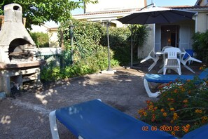 A patio with a stone oven, outdoor furniture, and a garden.