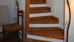 A staircase with wooden steps and white walls, a chair, a lamp, and a framed artwork. - Beach<100m. Air conditioning. Wifi. Enclosed garden. bbc. Parking.opt car. No. of activities (borgo)