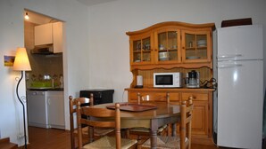 A compact kitchen with a dining table, chairs, a microwave, a coffee maker, and a refrigerator. - Beach<100m. Air conditioning. Wifi. Enclosed garden. bbc. Parking.opt car. No. of activities (borgo)