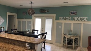 A kitchen with granite countertops, a dining area with a table and chairs, and a sign reading "BEACH HOUSE". - Relax and unwind in this Beautiful and Spacious smoke-free and pet-free home! (Port Bolivar)