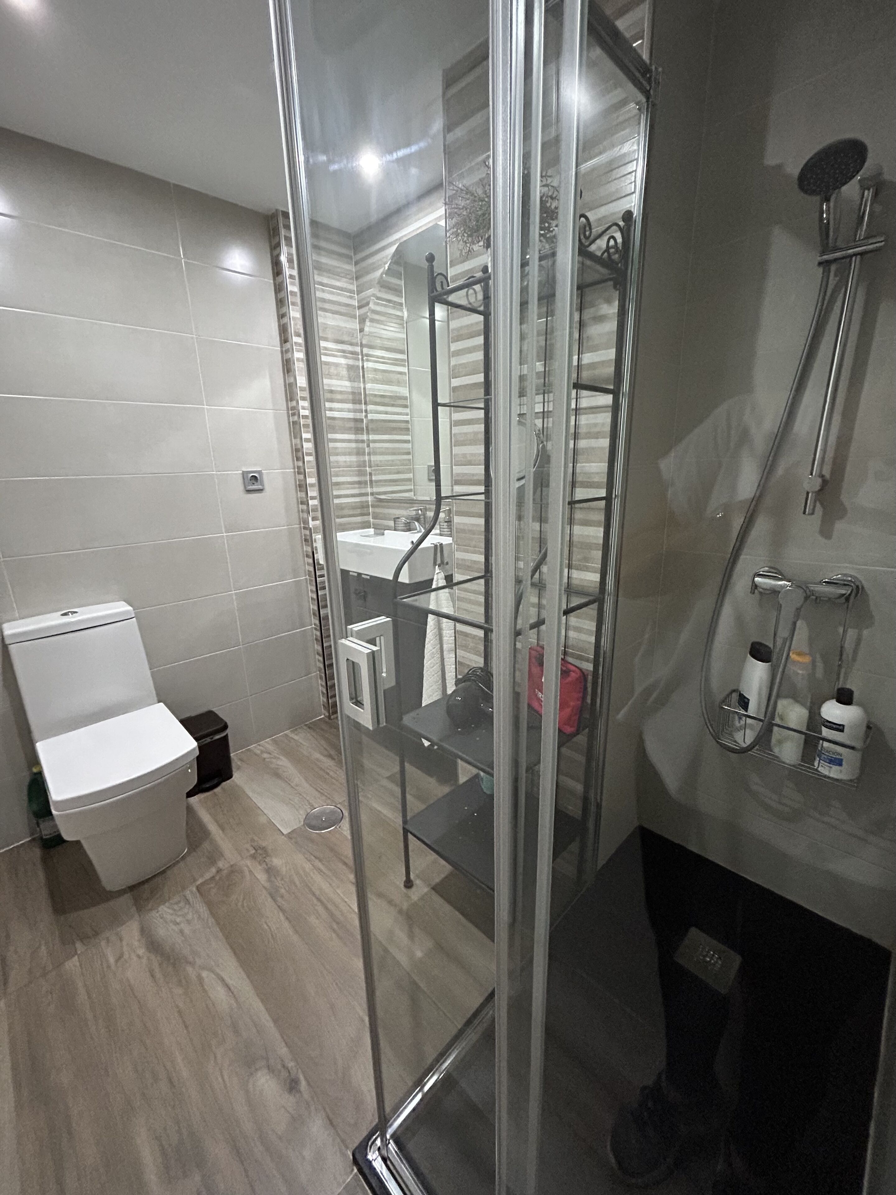 Ein modernes Badezimmer mit Duschkabine aus Glas, Toilette und Waschbecken.