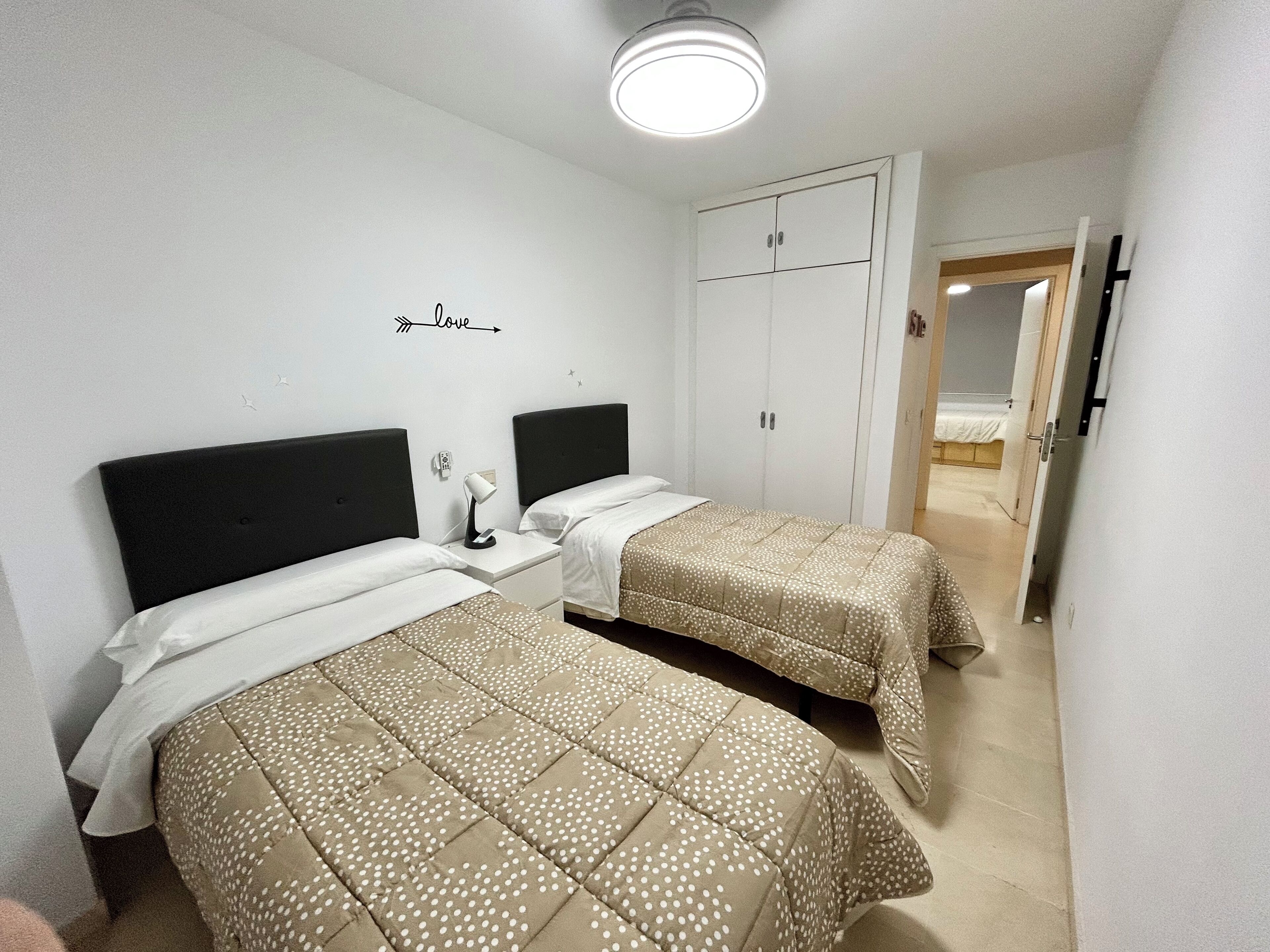 Ein Schlafzimmer mit zwei Betten, einem Kleiderschrank und einem Nachttisch mit einer Lampe.