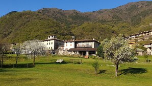 A rural village with traditional stone buildings, a grassy field, and a mountain backdrop.