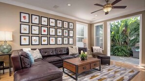 A living room with a sectional sofa, a coffee table, and a wall of framed artwork.