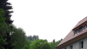 A paved courtyard with a building featuring a tiled roof and multiple windows.