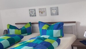 A bedroom with a bed, two pillows, a nightstand, and three wall decorations.