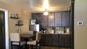A modern kitchen with dark wood cabinets, a granite countertop, and a dining area with two chairs.