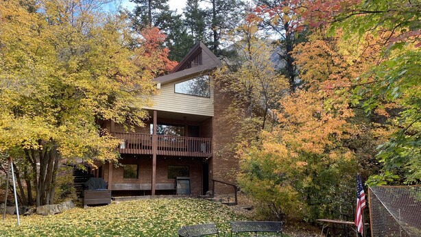 A two-story building with a balcony, surrounded by autumn foliage.